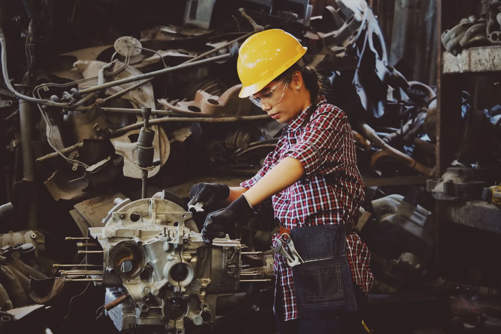Technician in a hard hat and safety glasses working on an engine block